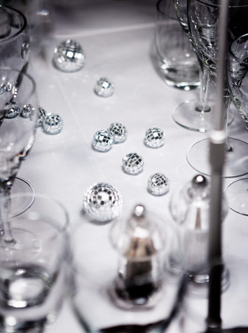 Instead of flowers, miniature disco balls decorate the table setting for Copenhagen Island Hotels White Christmas theme event. White porcelain and clear crystal glasses send associations to snow and ice.