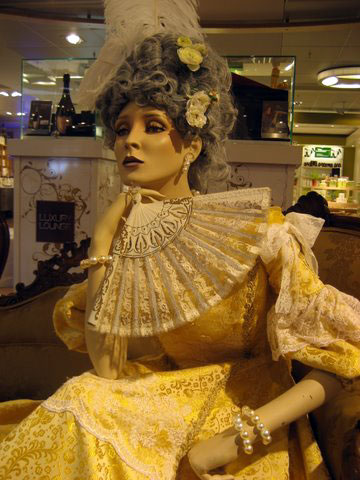 Detail of the styling of a decorative mannequin, dressed for the Copenhagen Airports fall event called The Luxury Lounge- notice her elaborate costume, wig with feathers and antique fan.